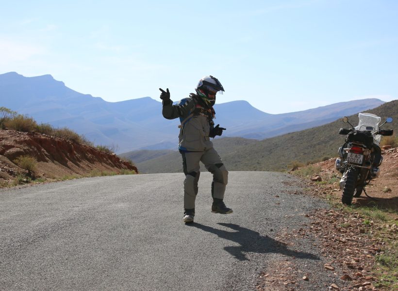 Motorcycle rider celebrating adventure on mountain road